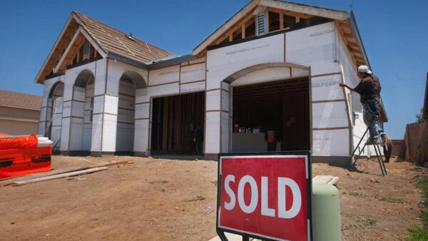 Picture of a house under construction with a sold sign in the foreground