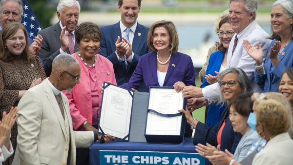 Nancy Pelosi is holding a signed bill outside with other members of Congress