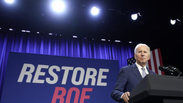 Joe Biden in front of a sign that says "Restore Roe"