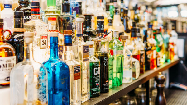 A shelf with a variety of alcohol on it behind a bar