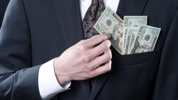 A man in a business suit pockets money.