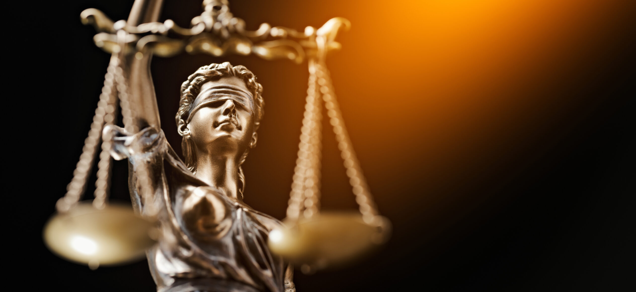 A bronze statue of Justice against a dark background.