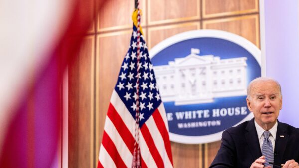 President Joe Biden is seen next to an American flag