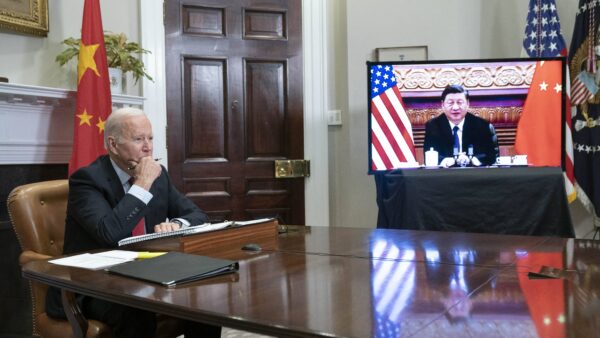 President Joe Biden sits in a room on a teleconference with China