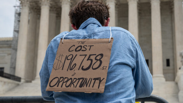 Student loan protester wears cardboard sign in front of the Supreme Court