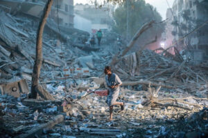 A lone person walks atop rubble in the wake of the war in Israel and Palestine