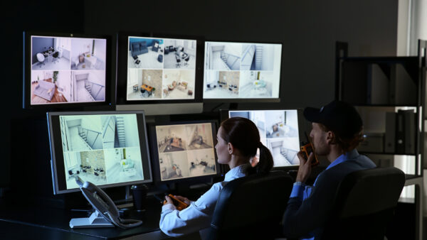Security guards monitor a bank of CCTV security cameras.