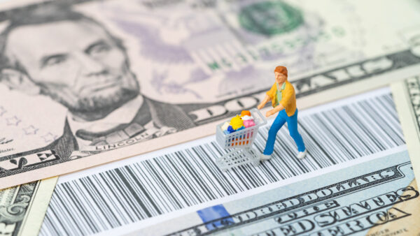 Miniature of a person grocery shopping on top of money and a barcode