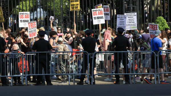Police officers stand on the other side of a line of barricades from a crowd of protesters at Columbia University.
