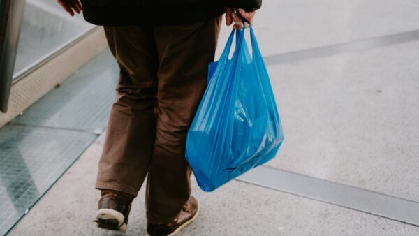 A person carries a blue plastic bag full of things