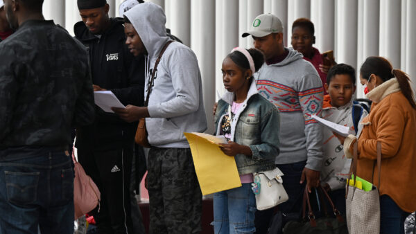 Migrants waiting in line with paperwork