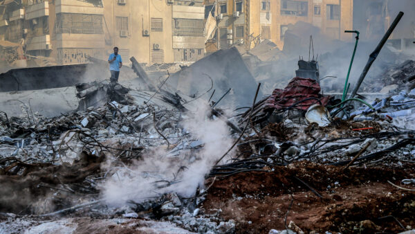 A Lebanese man stands among rubble, debris and smoke that is still billowing from the site of the massive Israeli air strike that killed pro-Iranian Hezbollah chief Hassan Nasrallah in Beirut's southern suburb.