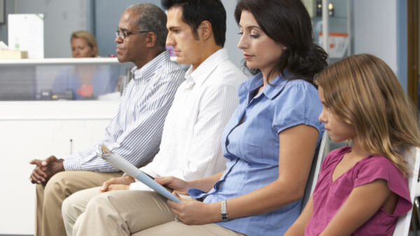 Seated patients in a row in a doctor's office waiting room.