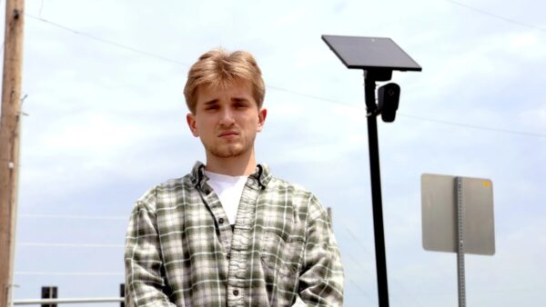 Mason Grimmett stands near an ALPR camera in Wichita